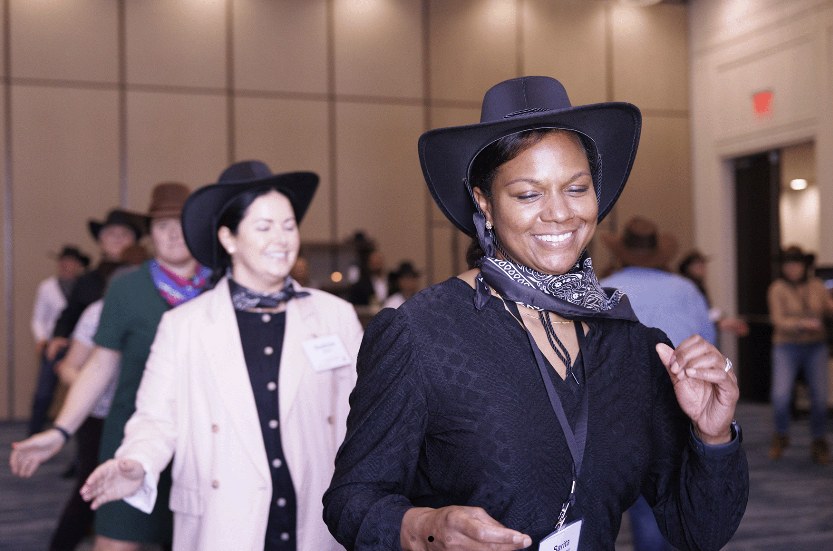 HealthLeaders Exchange members line dancing in cowboy hats at an event
